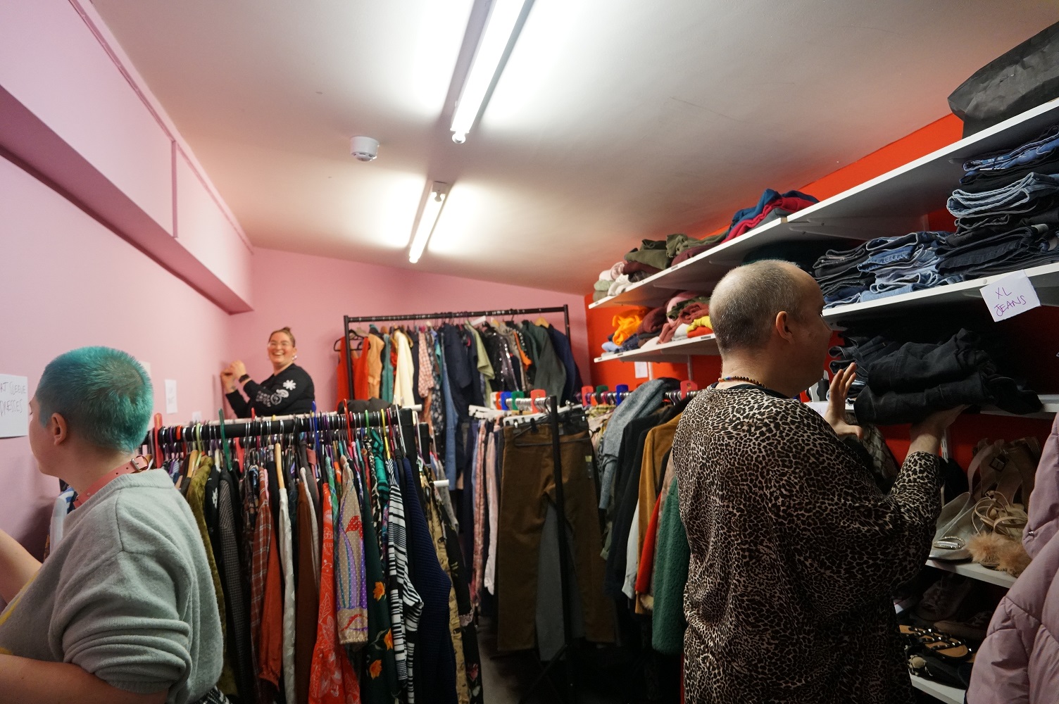 Three volunteers arrange clothing in the Wardrobe