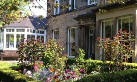 An external shot of Bensham Grove Community Centre, stone buildings set in a green garden with wildflowers 