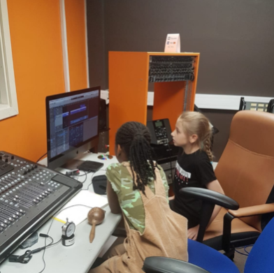 Two children working at a sound desk in a recording studio