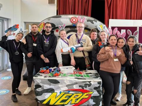A group of 10 young people are standing in front of an inflatable, holding NERF guns and wearing bunny ears