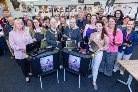 Mayor of Gateshead holding repurposed phones and laptops in a crowd of supporters 