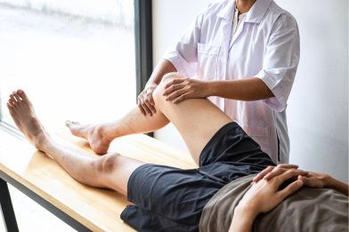 A patient receives physiotherapy on his legs, lying down on a medical bed